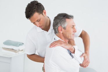 Chiropractor assesing middle aged male patient's thoracic spine