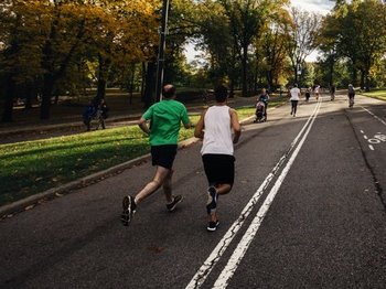 two men jogging through a park on a sunny day